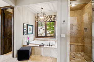 Full bath with a bath, a chandelier, and a stall shower