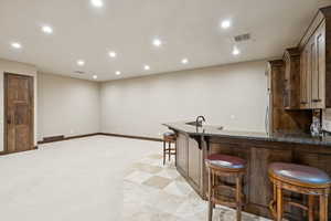 Indoor wet bar featuring recessed lighting, freestanding refrigerator, and stainless steel microwave