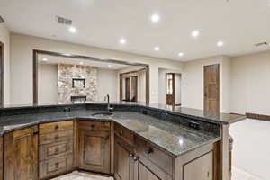 Kitchen with open floor plan, dark stone countertops, recessed lighting, and a stone fireplace