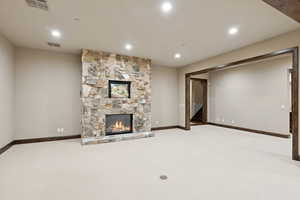 Unfurnished living room with carpet flooring, stairs, recessed lighting, and a stone fireplace
