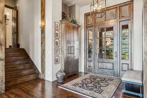 Foyer entrance featuring dark wood-style floors, a chandelier, and stairway