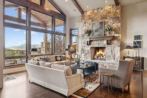 Living area with beamed ceiling, plenty of natural light, wood finished floors, a stone fireplace, and a mountain view
