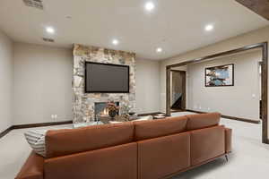 Carpeted living area featuring a stone fireplace and recessed lighting