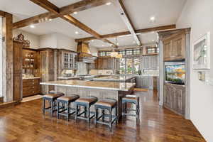 Kitchen with backsplash, beam ceiling, a kitchen bar, light stone countertops, and coffered ceiling