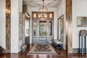 Entrance foyer with dark wood-style floors, a chandelier, and a high ceiling