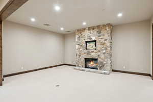 Unfurnished living room with carpet, recessed lighting, and a stone fireplace