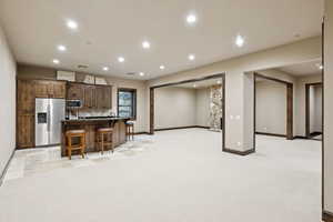 Kitchen with appliances with stainless steel finishes, a kitchen bar, recessed lighting, an island with sink, and tasteful backsplash