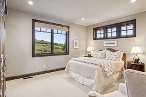 Carpeted bedroom with recessed lighting and multiple windows
