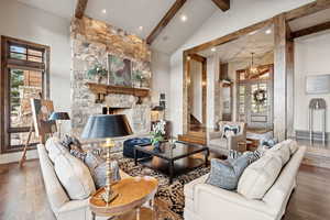 Living area with wood finished floors, healthy amount of natural light, recessed lighting, stairs, and a stone fireplace