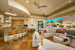 Living area with a tray ceiling, recessed lighting, and a ceiling fan