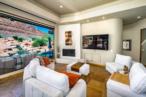 Living room featuring stone tile flooring, a high end fireplace, and recessed lighting