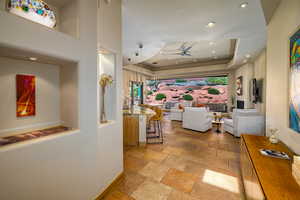 Hall featuring stone tile flooring, plenty of natural light, recessed lighting, and a tray ceiling