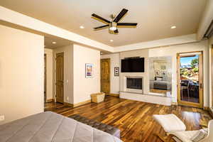 Bedroom featuring dark wood-type flooring, access to exterior, recessed lighting, and a fireplace with raised hearth