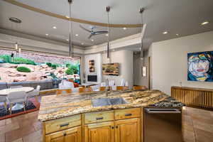 Kitchen featuring open floor plan, recessed lighting, light stone counters, ceiling fan, and stone tile flooring