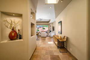 Corridor with stone tile flooring, built in features, and recessed lighting
