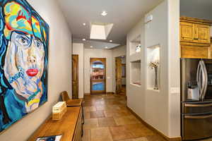 Hall with stone tile floors and recessed lighting