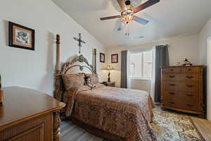 Bedroom featuring light wood-type flooring, vaulted ceiling, and ceiling fan