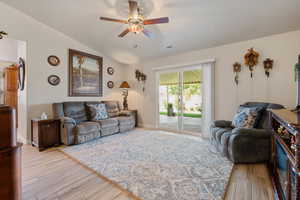 Living room with ceiling fan, wood finished floors, and lofted ceiling