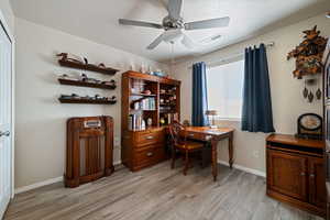 Office with light wood-type flooring and ceiling fan