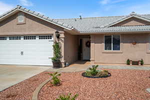 Ranch-style home with stucco siding, an attached garage, driveway, and a tile roof