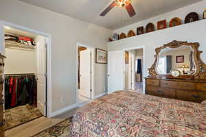 Bedroom with a walk in closet, light wood-style flooring, a closet, and ceiling fan