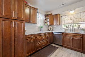Kitchen with dishwasher, open shelves, decorative backsplash, light wood finished floors, and light stone countertops