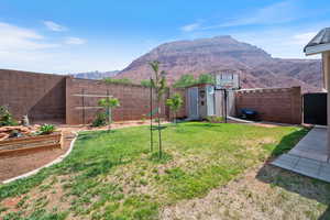 Fenced backyard with a garden, a storage shed, and a mountain view