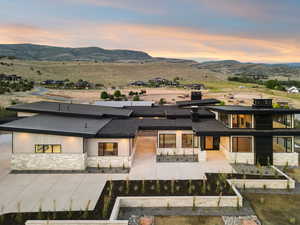 Rear view of property with stone siding, a mountain view, and a vegetable garden