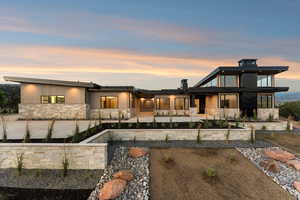 Back of house at dusk with stone siding