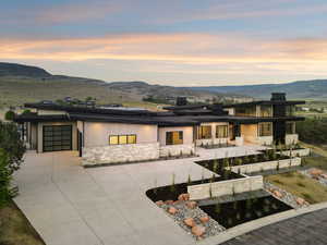 Back of house at dusk with stone siding, roof mounted solar panels, a mountain view, and a garage