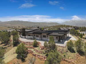 Rear view of house featuring stone siding, a patio, a mountain view, stucco siding, and a chimney
