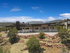 Back of property with stone siding, a mountain view, and a patio
