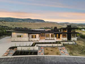 View of front of property with stone siding, a mountain view, a patio, roof mounted solar panels, and a garden