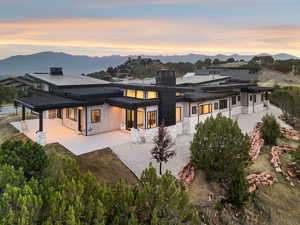 Rear view of property with a patio, a mountain view, a standing seam roof, and stone siding