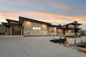 Contemporary house featuring stone siding, a garage, and concrete driveway