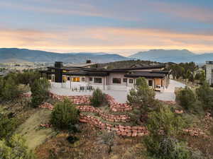 Rear view of property with a patio, a mountain view, a chimney, and stone siding