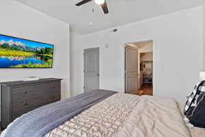 Bedroom featuring a walk in closet, wood finished floors, and ceiling fan
