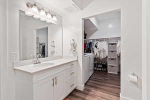 Bathroom with washer and clothes dryer, vanity, a spacious closet, and wood finished floors