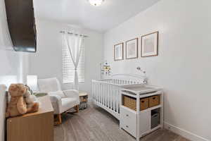 Carpeted bedroom with baseboards and a crib