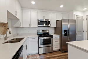 Kitchen with appliances with stainless steel finishes, white cabinetry, light countertops, wood finished floors, and recessed lighting