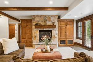 Living room featuring beamed ceiling, a fireplace, and recessed lighting