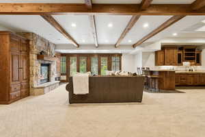 Living area featuring beam ceiling, a fireplace, recessed lighting, and light carpet