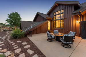 Rear view of house featuring board and batten siding, a shingled roof, a fire pit, and a patio area