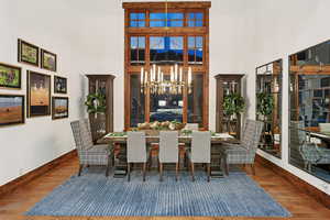 Dining area featuring a towering ceiling, wood finished floors, a chandelier, and a mountain view