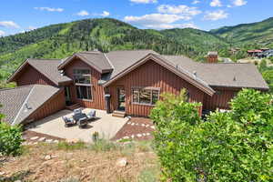 Back of property with board and batten siding, a mountain view, a patio area, and a chimney