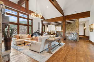 Living area with wood-type flooring, high vaulted ceiling, beamed ceiling, and a chandelier