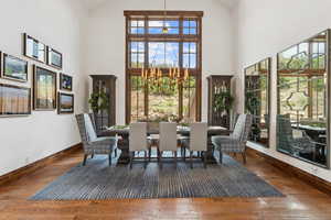 Dining area with wood finished floors, a chandelier, and high vaulted ceiling