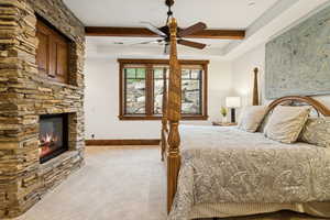 Bedroom featuring a fireplace, carpet floors, beamed ceiling, and a ceiling fan