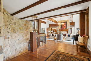 Hall featuring hardwood / wood-style flooring, an upstairs landing, a chandelier, and beamed ceiling