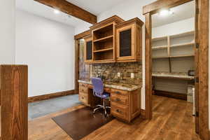 Office area featuring built in study area, beam ceiling, and dark wood finished floors